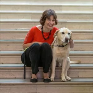 Nicki sitting on steps with guide dog.
